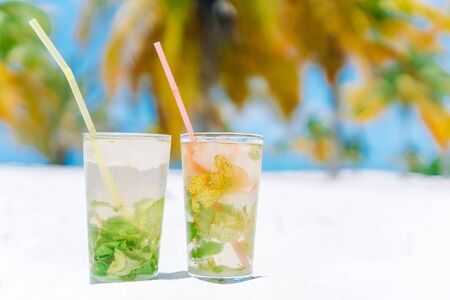 Two cold tasty mohito cocktails on the white sandy beach in palm groveの写真素材