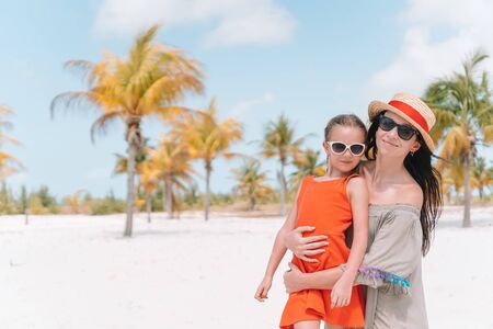 Little cute girl and young mother at tropical beachの写真素材
