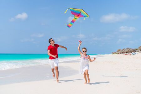 Family flying kite together at tropical white beachの写真素材