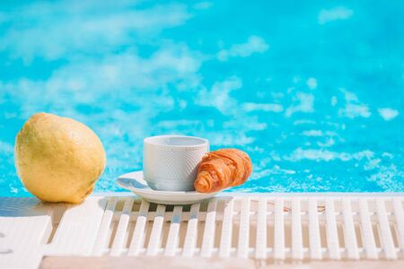 Delicious breakfast lemon, coffee, croissant by the poolの写真素材
