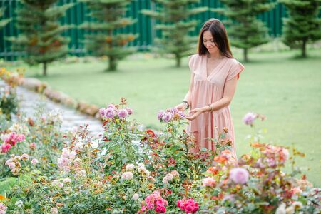 Young girl in a flower garden among beautiful roses. Smell of rosesの写真素材