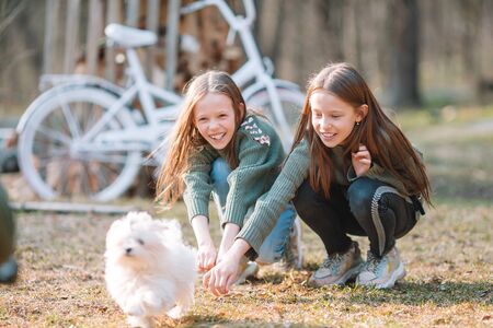 Little girls with a white puppy. A puppy in the hands of a girlsの写真素材