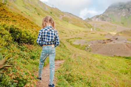 Beautiful happy little girl in mountains in the background of fog