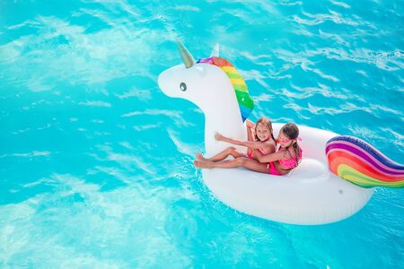 Adorable little girls at swimming pool having fun during summer vacation