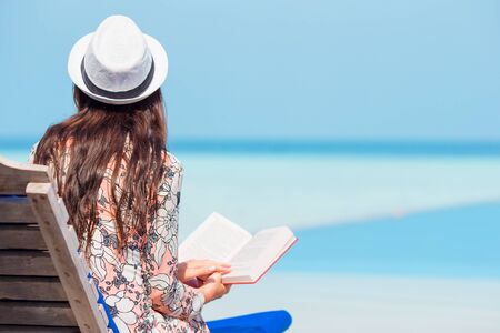 Portrait of a young woman relaxing on the beach, reading a bookの写真素材