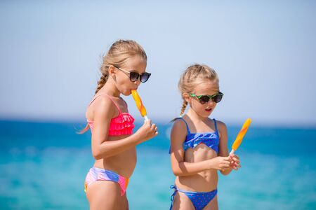 Happy little girls eating ice-cream during beach vacation.の写真素材