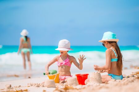Mother and little daughters making sand castle at tropical beachの写真素材