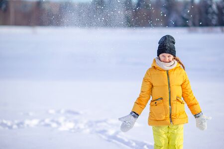 Portrait of little adorable girl in snow sunny winter day