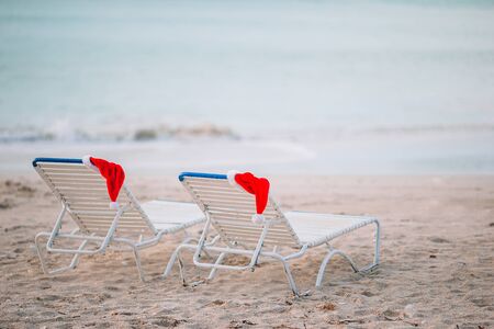 Santa hats on chair longues at tropical white beachの写真素材