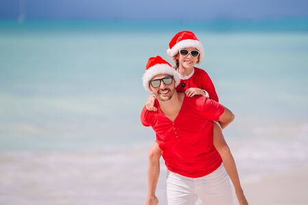Father and daughter in Santa Hat have fun at tropical beachの写真素材