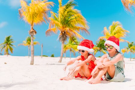 Little adorable girls on the sandy beach under palmtreesの写真素材