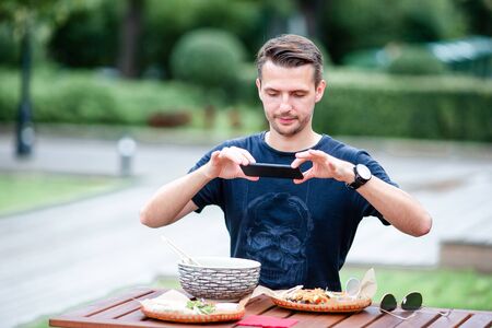 Young man eating take away noodles on the streetの写真素材