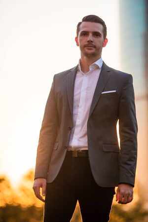Businessman looking on copy space while standing against glass skyscraperの写真素材