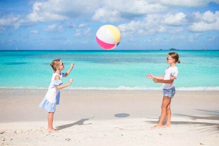 Little adorable girls playing with ball on the beach. Kids having fun on the seashoreの写真素材