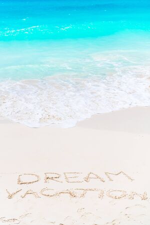Dream written on sandy beach with soft ocean wave on backgroundの写真素材