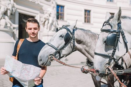 Man tourist with a city map and backpack in Europe street. Caucasian boy looking with map of...