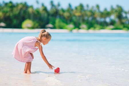 Little adorable girl playing on beach with ballの写真素材