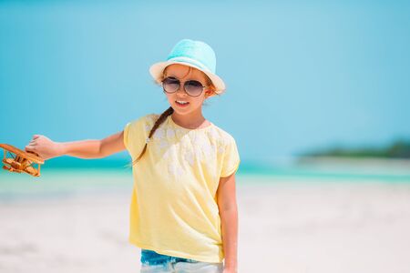 Happy little girl with toy airplane in hands on white sandy beach.の写真素材