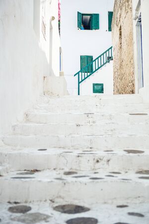 The narrow streets of the island with blue balconies, stairs and flowers in Greece.の写真素材