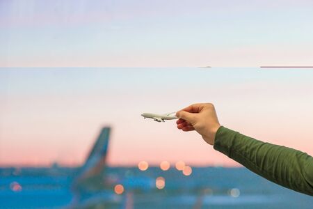 Close up hand holds an airplane model on background of big windowの写真素材