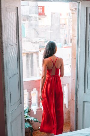 Young beautiful woman in red dress on old balcony in apartments in Havana at Cubaの写真素材