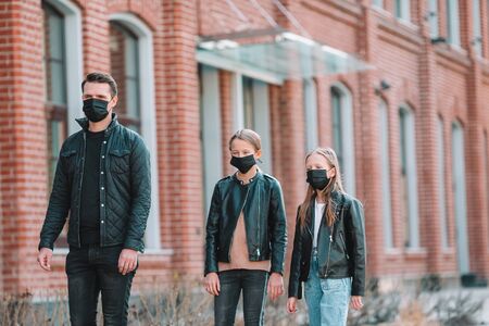 Family wearing masks on the street in an empty city. Protection against Coronavirus and gripp. Kids keep distance with each otherの写真素材