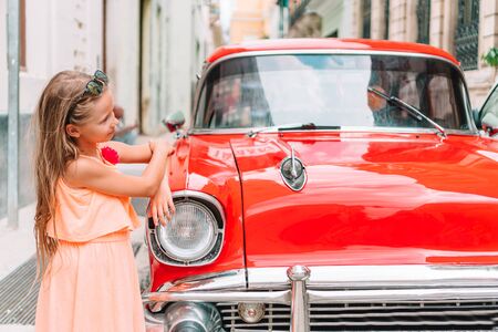 Adorable little girl in popular area in Old Havana, Cuba. Portrait of kid with vintage classic...
