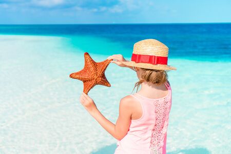 Adorable little girl with starfish on the beachの写真素材