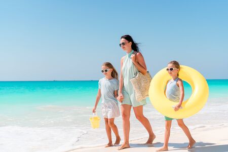 Adorable little girls and young mother on white beach. Family on the beach ready to swimの写真素材