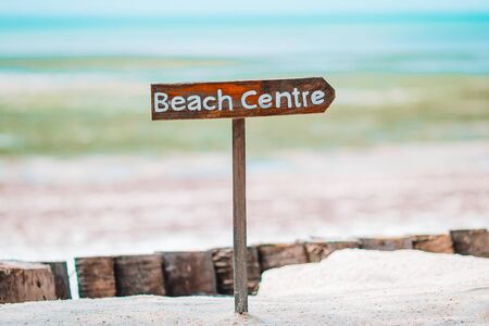 Idyllic tropical beach with white sand, turquoise ocean water with beach sign