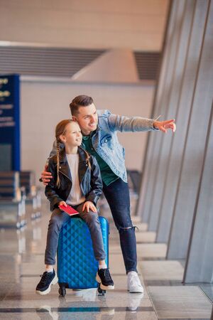 Young father and little daughter looking out the window at airport terminal waiting for boardingの写真素材