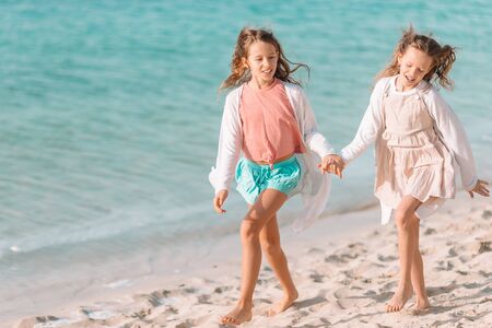 Little girls having fun at tropical beach having fun and runningの写真素材