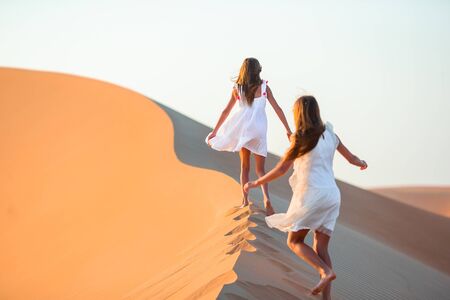 Little girls on vacation at dunes in desertの写真素材