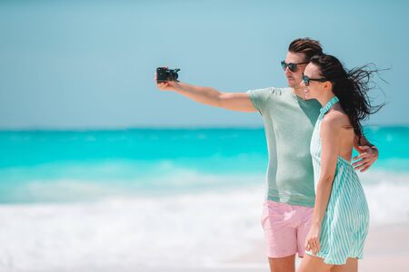 Happy couple taking a photo on white beach on honeymoon holidayの写真素材