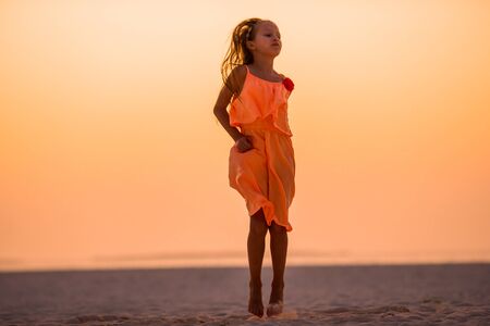 Adorable happy little girl on white beach at sunset.の写真素材