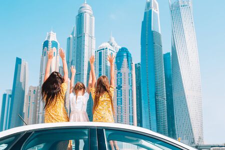 Family summer vacation. Mom and kids on car vacation on background of skyscrapers in Dubaiの写真素材