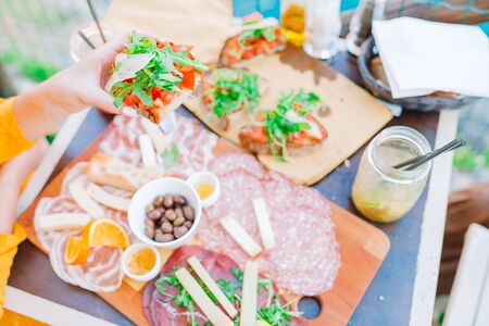Tasty italian snacks. Fresh bruschettes, cheeses and meat on the board in outdoor cafe with amazing view in Manarola, Italyの写真素材