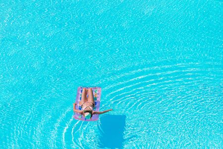 Beautiful young woman relaxing in swimming pool.