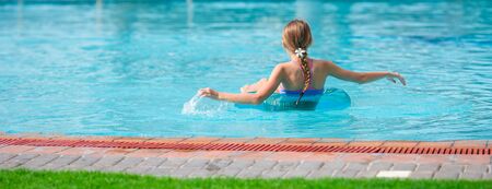 Panorama of little happy adorable girl in outdoor swimming poolの写真素材