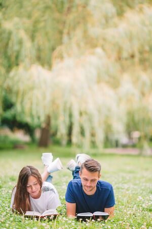Young romantic couple lying in park and reading booksの写真素材