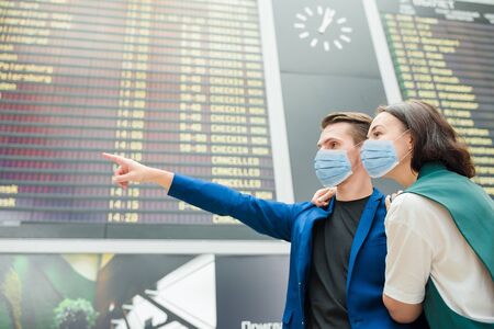 Young couple in international airport looking at the flight information boardの写真素材