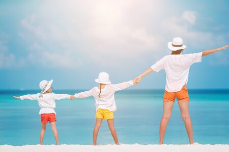 Adorable little girls and young mother on tropical white beachの写真素材