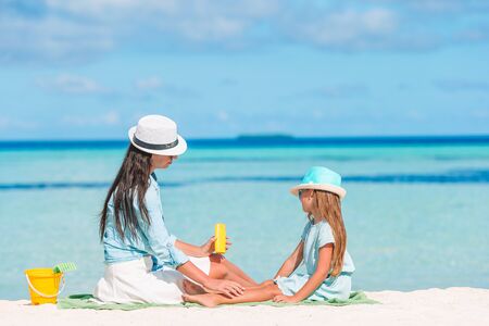 Young mother applying sun cream to daughter nose on the beach. Sun protectionの写真素材