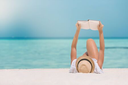 Young woman reading book on the beachの写真素材