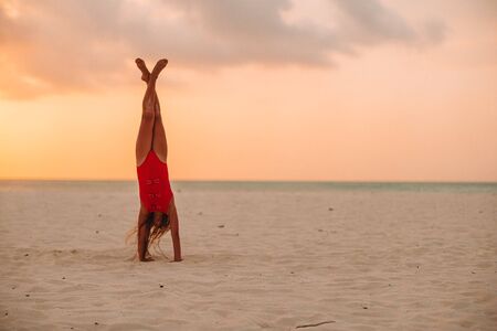 Adorable happy little girl on white beach at sunset
