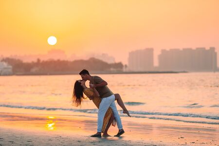 Family vacation. Young couple enjoy beach at sunset kissingの写真素材