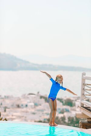 Adorable little girl on the edge of outdoor swimming poolの写真素材