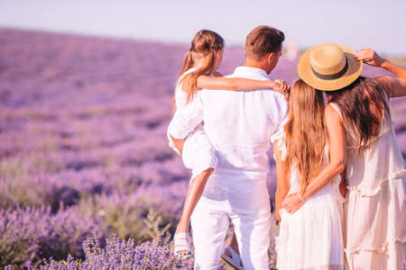 Family in lavender flowers field at sunset in white dress and hat