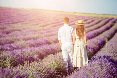 Family in lavender flowers field at sunset in white dress and hatの写真素材