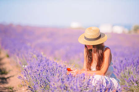 Woman in lavender flowers field at sunset in white dress and hatの写真素材